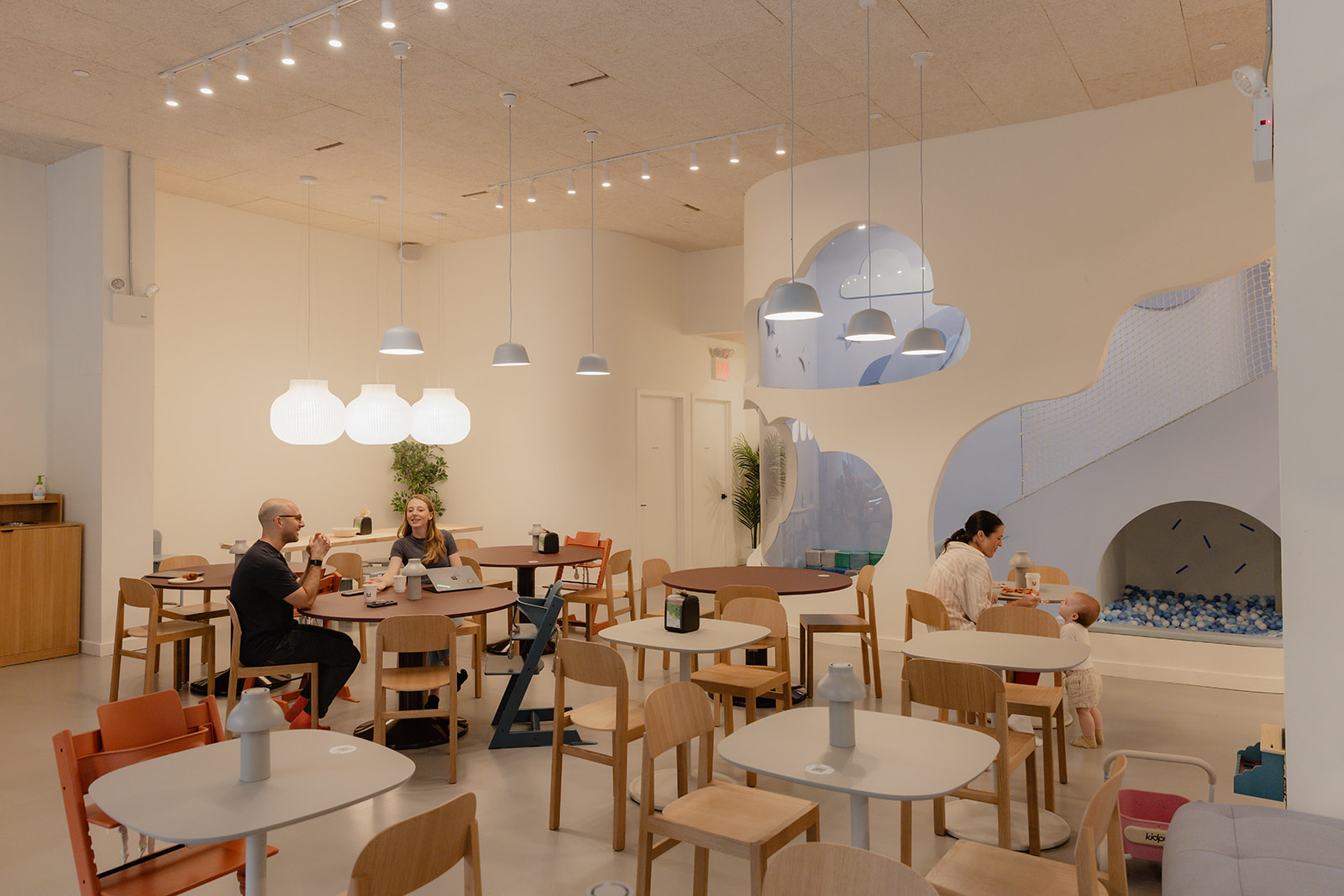The café interior at House of Wonder on Fulton Street in Clinton Hill, Brooklyn. Parents work at café tables while a child plays in the adjoining ball pit.