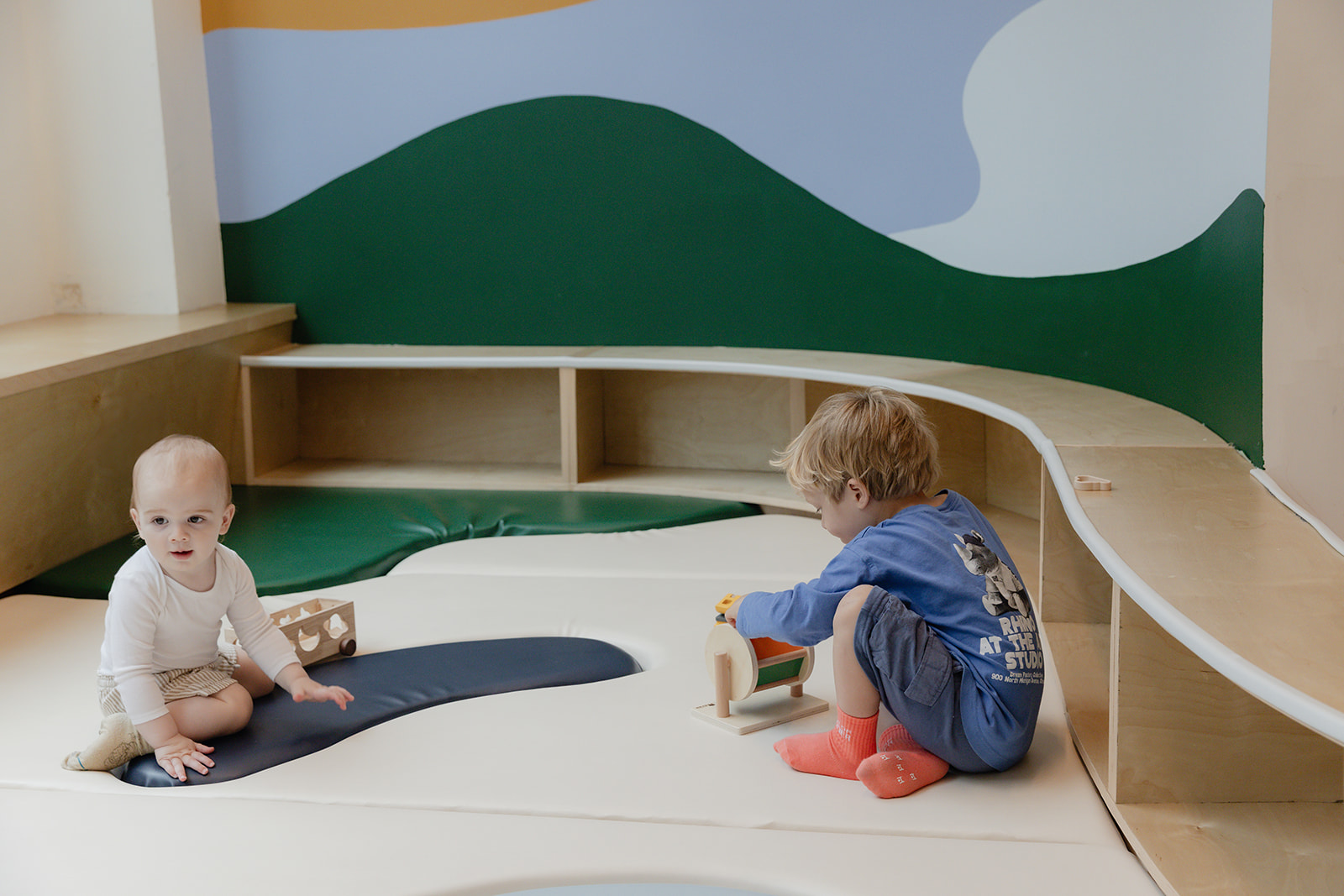 Two young children playing in the soft-floor play area at House of Wonder.